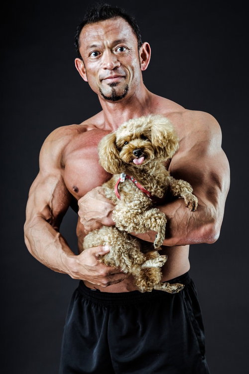 子犬を優しく抱くボディビルダー