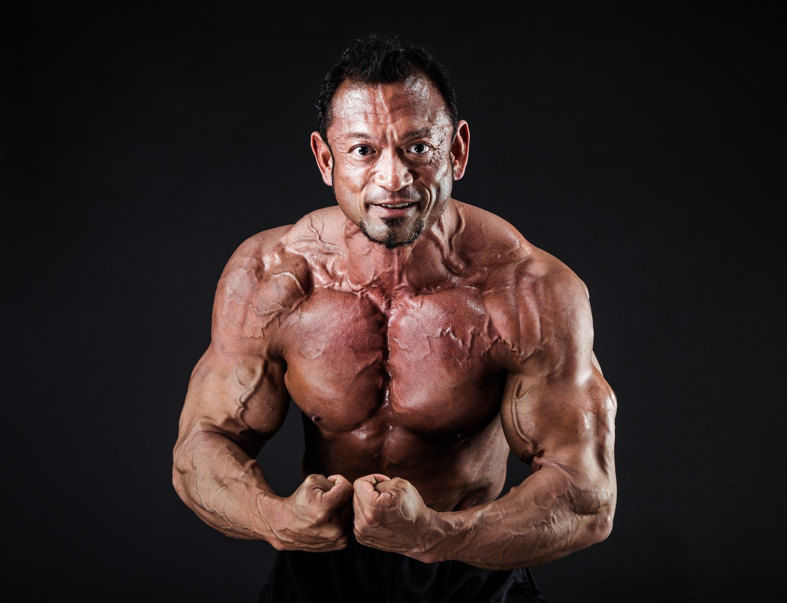 黒い背景でモスト・マスキュラーのポージングを決めるボディビルダーの男性［モデル：パルンボ井若］