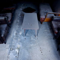 廃屋の応接室跡、埃まみれのテーブルとソファーの写真