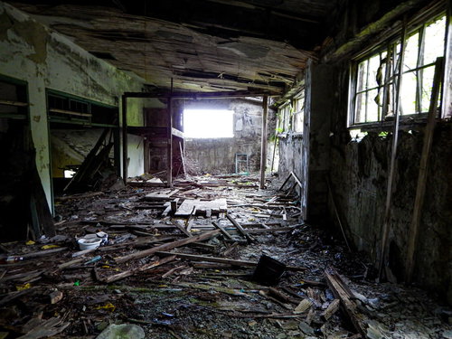 ボロボロの廃墟と瓦礫の山、散乱する木材と破片