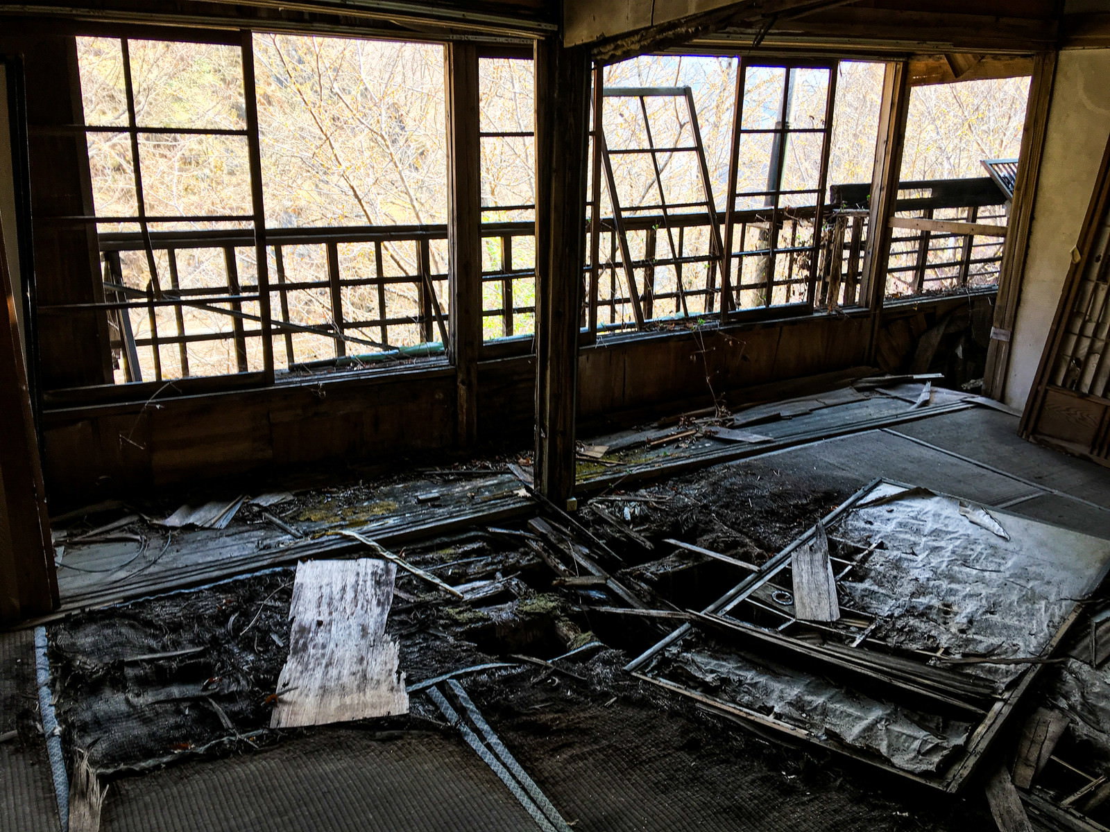 床が崩れ落ち瓦礫が散乱した朽ち果てた廃屋の室内