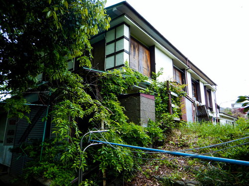 廃業した空き旅館と緑に覆われた建物、苔やツタが付着した和風建築