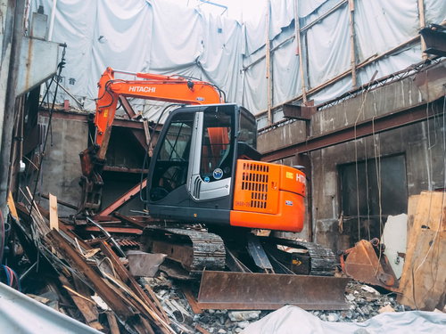 解体途中の家とオレンジ色のショベルカーによる重機作業