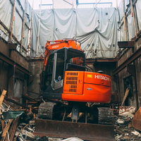 廃墟の建物を解体していくオレンジのショベルカーの写真