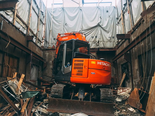 廃墟の建物を解体していくオレンジのショベルカー