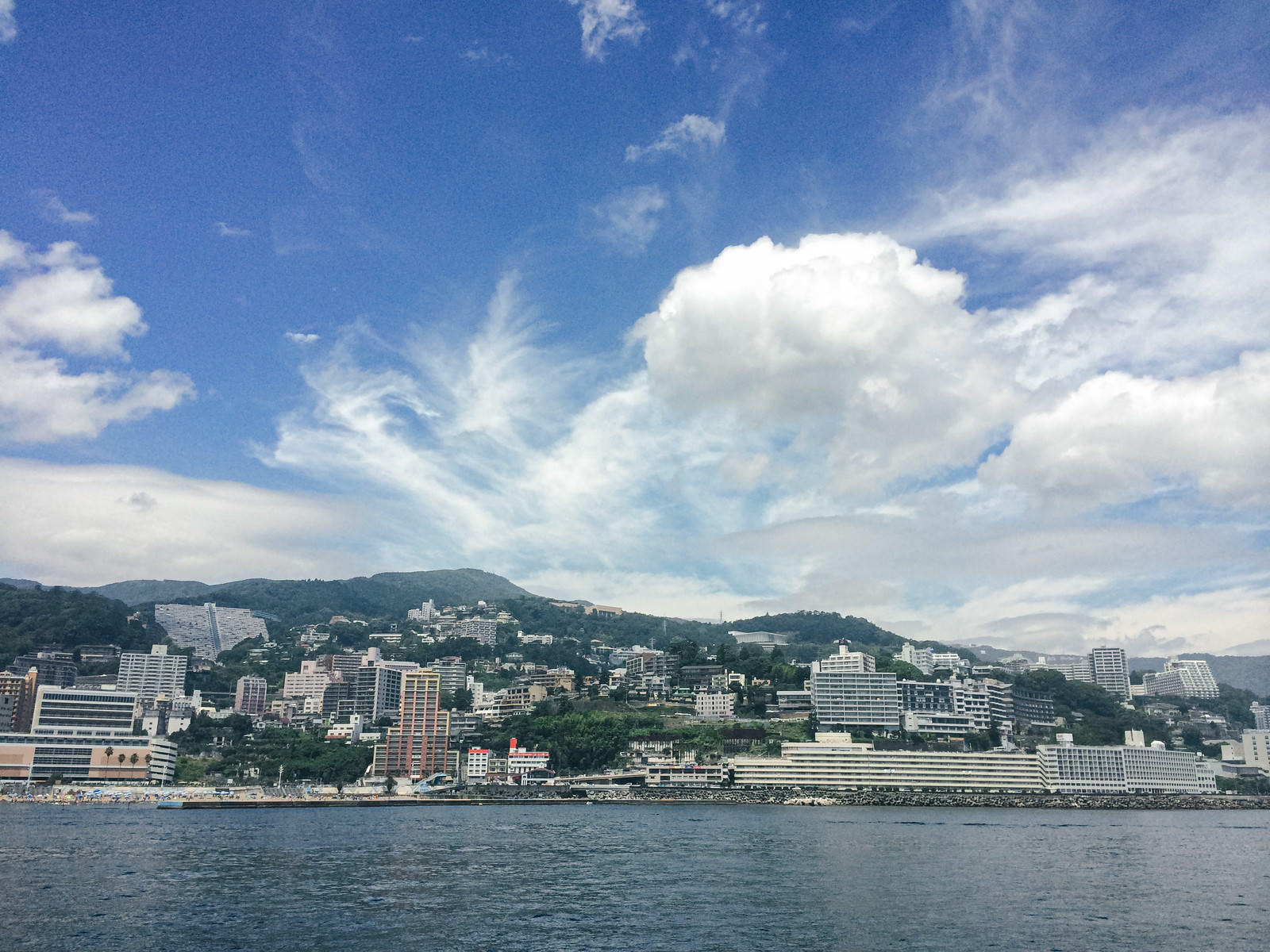 相模湾に面した熱海の街並みと青空に白い雲が浮かぶ風景