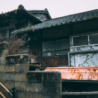 蔦に侵食された古民家の外壁とブロック塀、昭和の平屋建ての写真