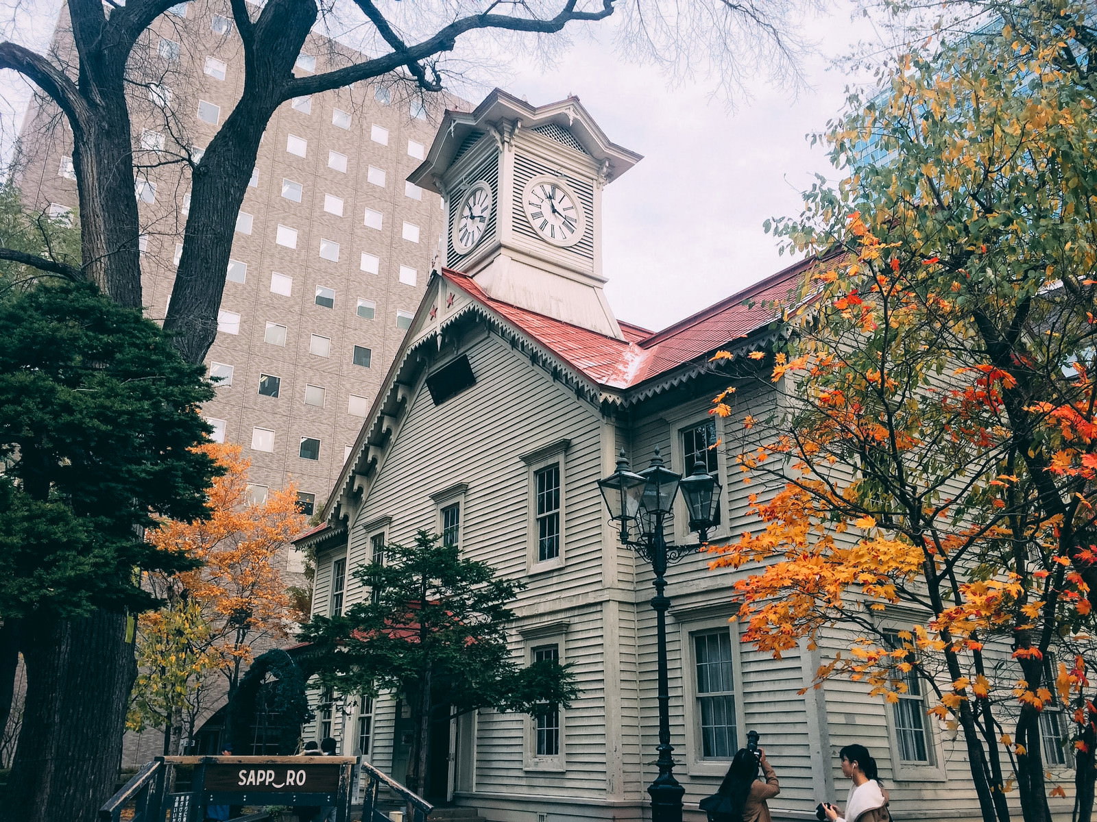 紅葉の木々に囲まれた札幌時計台の白い建物と赤い屋根