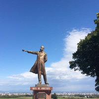 羊ケ丘展望台に立つクラーク像と札幌の景観の写真