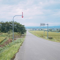 北海道の田園地帯を貫く長い一直線の道路と矢羽根付きポールの写真