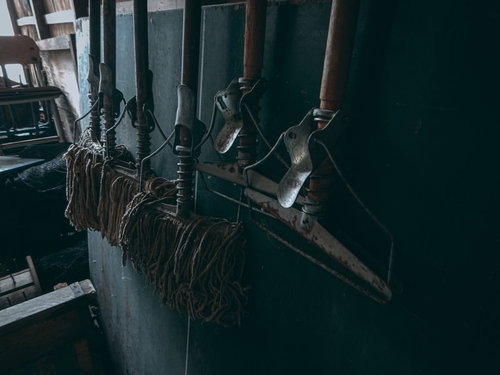 薄暗い廃墟の学校で壁に吊るされたボロボロのモップ