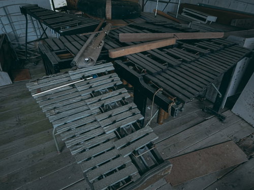 廃校の音楽室に置かれたくたびれた鉄琴と散らばったバチ