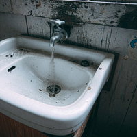 水が流れることはもうない廃校の古い蛇口と洗面台の写真