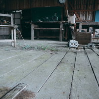 廃校の教室に残された荒れ果てた木製床と散らばる学用品の写真