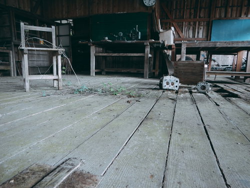 廃校の教室に残された荒れ果てた木製床と散らばる学用品