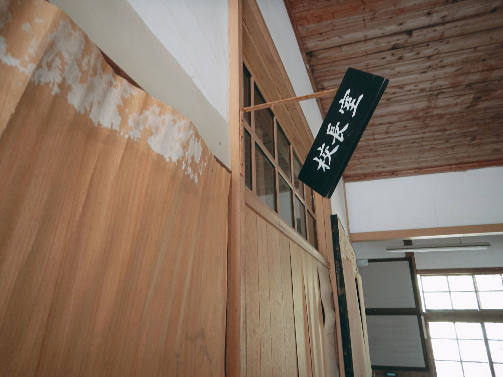 老朽化した廃校の校長室、木造の壁と天井、窓からの光