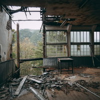 朽ちて倒壊しそうな廃校の教室の中、天井が大きく崩れ落ちた荒廃した室内の写真