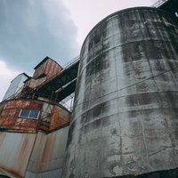 鉄琴コンクリート曲線美の工場タンク群と配管システムの写真