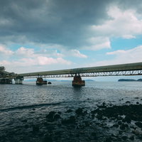 海に架かる橋と工場施設が形成する産業景観の写真