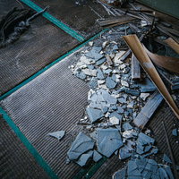 野ざらしの畳とコンクリート片が散乱する廃墟の写真