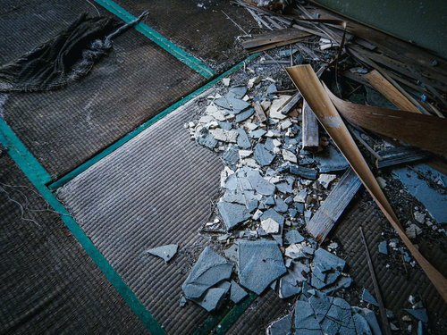 野ざらしの畳とコンクリート片が散乱する廃墟