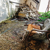 朽ち果てていく椅子と散らばる木材の写真