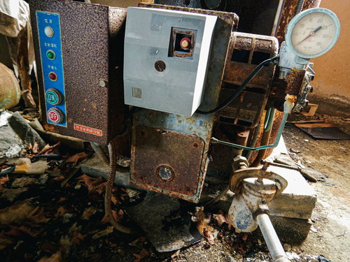 廃墟ホテルの錆びたコンパクト操作盤と配管設備