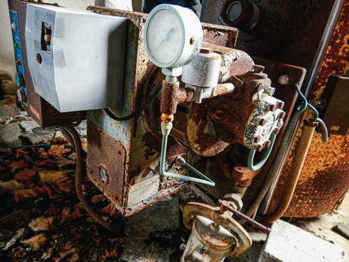 廃墟ホテルの錆びた循環装置のような機器と配管設備