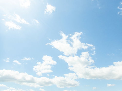 頭上の太陽と澄んだ青空に浮かぶ白い雲