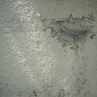 白い塗装が剥がれてコンクリートが露出した老朽化した壁の写真