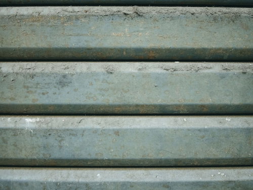 ほこりや塵がこびり付く緑色の古いシャッター