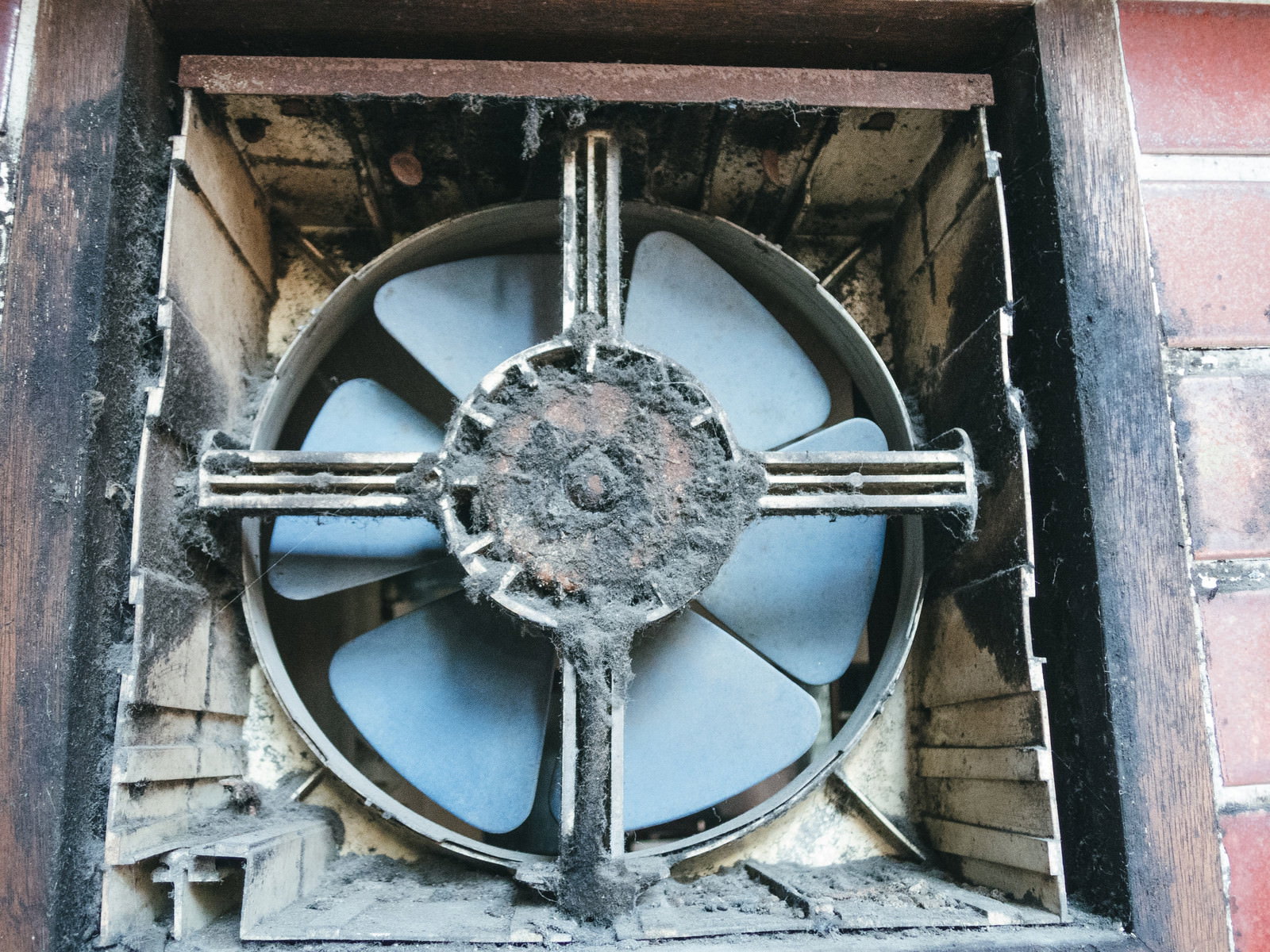 長期間掃除されずほこりや汚れが蓄積した古い換気扇のプロペラファン