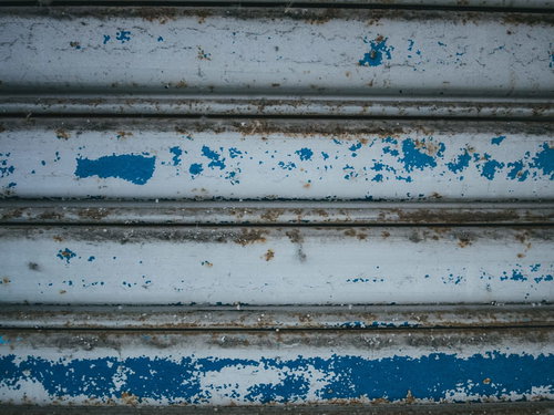 青い塗装が剥がれた金属シャッターのテクスチャー