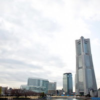 青空の下にランドマークタワーがそびえるみなとみらいの遠景の写真