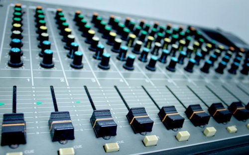 つまみやフェーダーが並ぶ音楽スタジオのミキサー卓の接写