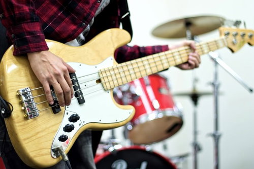 スタジオでベースギターを弾いてバンド練習する男性の手元
