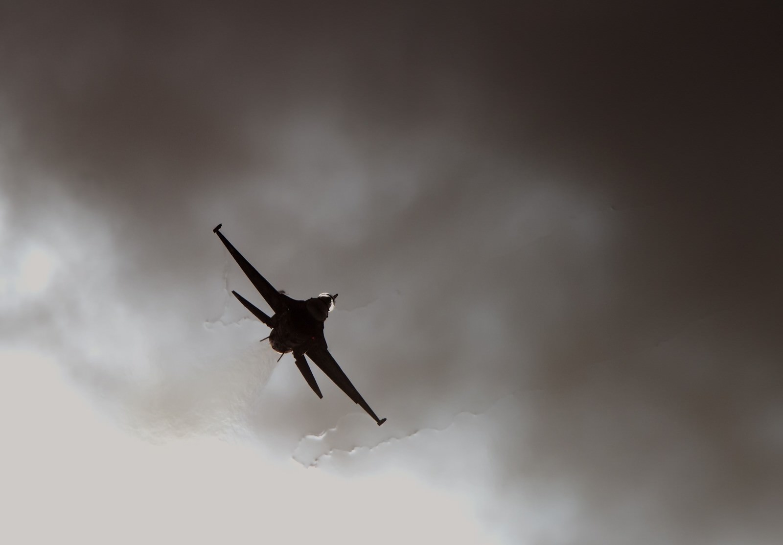 曇り空で急旋回する戦闘機のシルエット