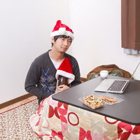 クリスマスにこたつで寂しく一升瓶を抱えて過ごす男性の写真