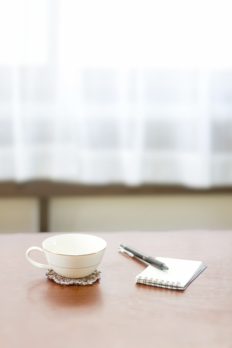 テーブルのコーヒーとメモ帳とペン
