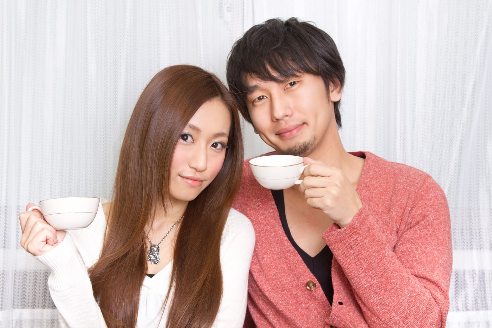 コーヒーカップを持つ笑顔の若い夫婦［モデル：大川竜弥 北野佑々］