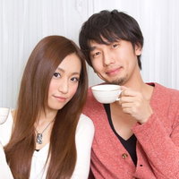 笑顔で並んでコーヒーカップを持つ若い夫婦の写真