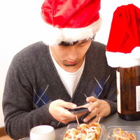 スマホを確認するサンタ帽のクリぼっちの写真