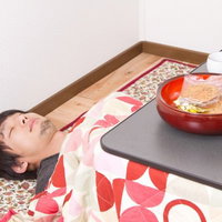 こたつの中に体を沈めて頭だけ出すこたつむりの男性の写真