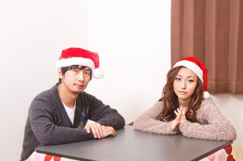 赤いサンタ帽子をペアでかぶって笑い合う男女のカップル