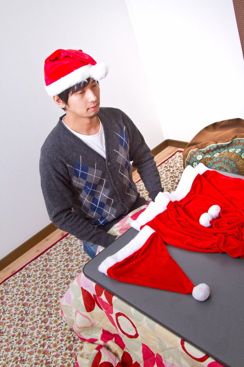 女性用サンタ衣装を広げたまま一人で過ごすクリぼっちの男性