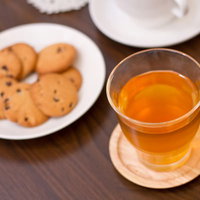 白いカップの紅茶と小皿のクッキーが並ぶティータイムの写真