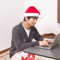 クリスマスにこたつの上でノートPCを開いて過ごす一人の男性の写真