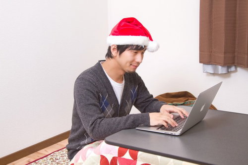 クリスマスにこたつの上でノートPCを開いて過ごす一人の男性