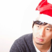 赤いサンタ帽子をかぶって正面を向く笑顔の男性の写真