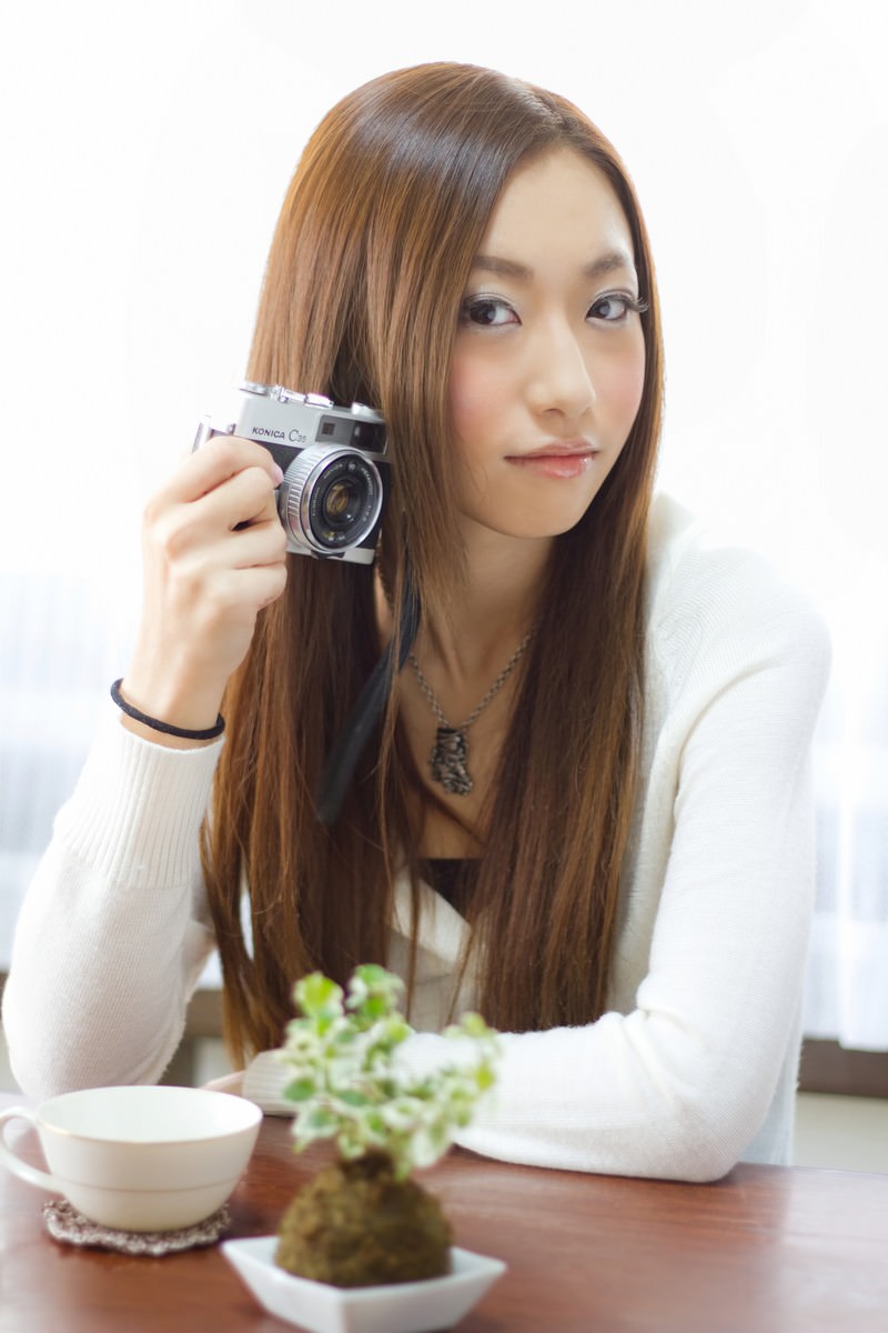 レトロカメラを構えるおしゃれな女性［モデル：北野佑々］